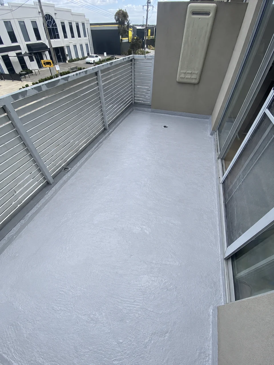 Completed waterproofing membrane across a balcony floor and perimeter junctions