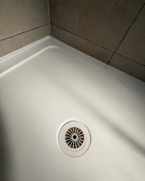 Same shower base and drain after the cracked surface and perimeter seal were repaired
